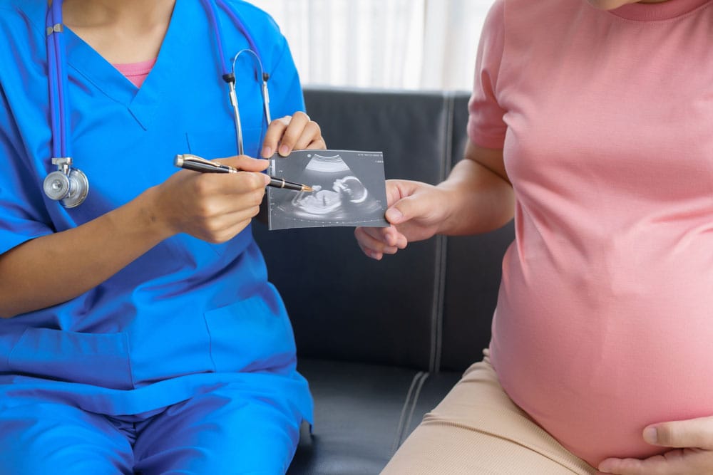 Hamile anne adayı klinikte hemşiresiyle görüşüyor