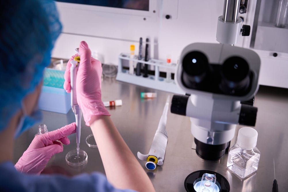 Embriyoloji laboratuvarında mikroskop ve pipetle sperm örneği inceleyen uzman